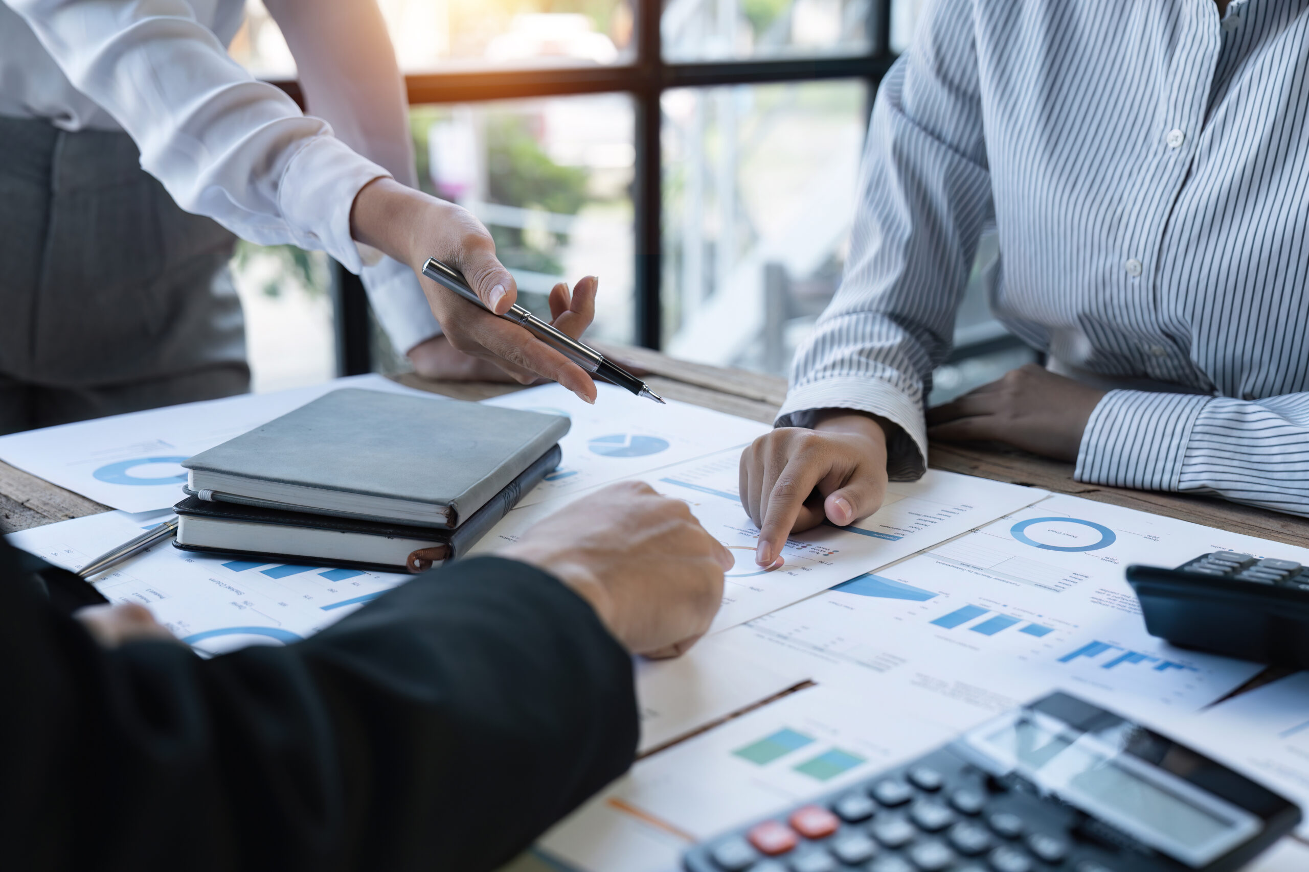 Diverse businesspeople cooperate work together discussing company financial statistics, multiracial colleagues employees collaborate brainstorm with finance document at meeting. close up shot